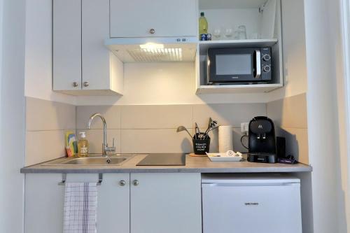 Una pequeña cocina con fregadero y microondas. en Le Petit Pithou - studio équipé simple et plein coeur de la ville 2, en Troyes