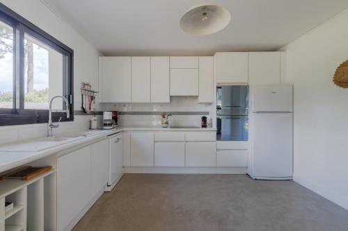  La cuisine est équipée de placards blancs et d'un réfrigérateur. dans l'établissement LA BOUSSOLE- Maison 8 personnes, à Pornichet