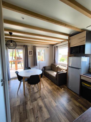 a kitchen and living room with a table and a couch at Village Vacances Les Sables d'Or in Gouville-sur-Mer