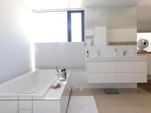 a white bathroom with a sink and a mirror at Penthouse Strand in Strand