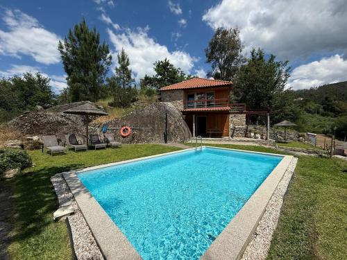 a swimming pool in front of a house at Quinta Encosta do Penedo - Wellness Retreat - Gerês in São Jorge