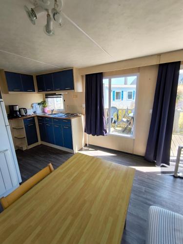 a kitchen with a table and a large window at Village Vacances Les Sables d'Or in Gouville-sur-Mer