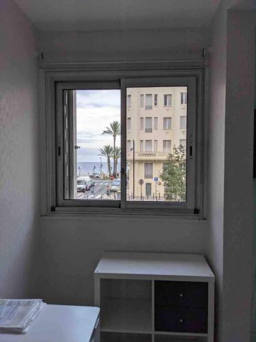 - une fenêtre dans une chambre avec une table et un bâtiment dans l'établissement Spacious 2 BR 1 block from beaches - and the TRAM, à Nice