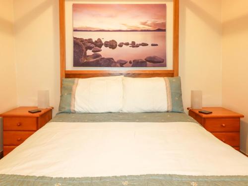 a bedroom with a bed with a painting above it at Barn Cottage in Liskeard
