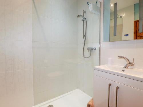 a white bathroom with a shower and a sink at Barn Cottage in Liskeard