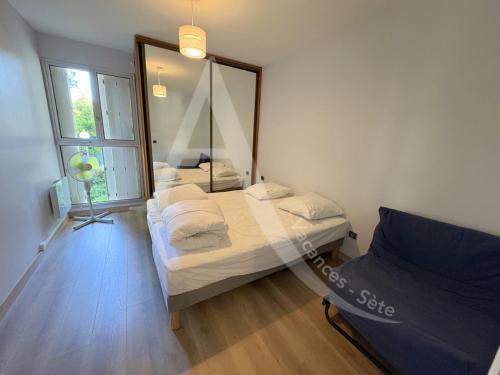 une chambre avec deux lits et un grand miroir dans l'établissement Spacieux T2 avec acces internet a proximite des plages, à Sète
