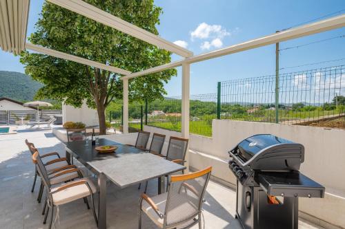 a patio with a table with a grill and chairs at Villa Magnolia with heated Pool and Jacuzzi, near sea in Tugare