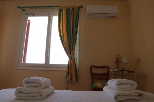 a bedroom with towels on a bed with a window at Villa Luminosa Kyra Panagia in Kyra Panagia