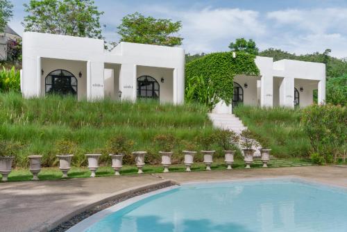 an exterior view of a white house with a swimming pool at Villa La Flora Kaeng Krachan in Kaeng Krachan