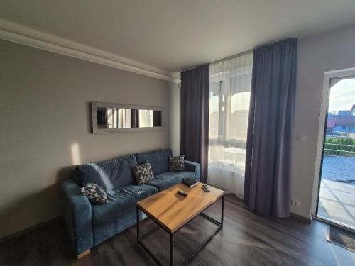 a living room with a blue couch and a coffee table at Apartament Holiday Haven in Rewal