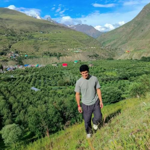 a man walking on a hill overlooking a valley at Rupi Rani Home Stay in Gushāl