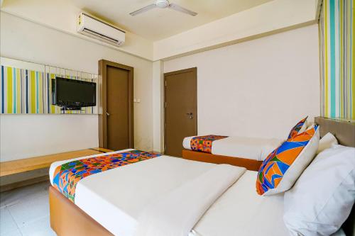 a hotel room with two beds and a flat screen tv at FabHotel Gargi Deluxe in Pune