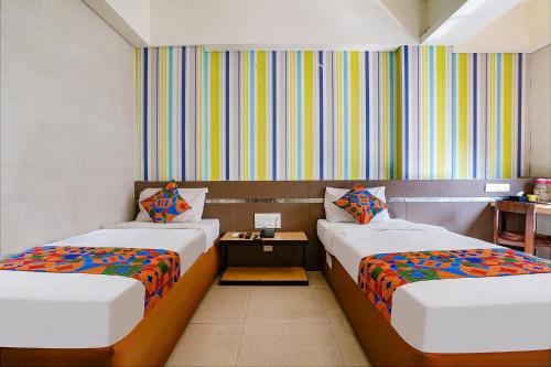 a room with two beds and a table at FabHotel Gargi Deluxe in Pune