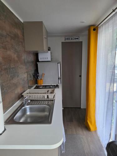 a kitchen with a stainless steel sink and a stove at Valras Cabane du Soleil Mobil home cosy in Sérignan
