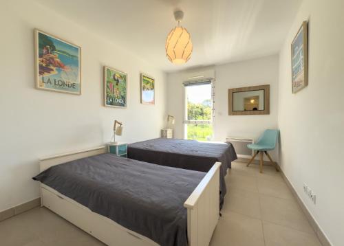 une chambre avec deux lits et une chaise bleue dans l'établissement appartement chic LA LONDE LES MAURES, à La Londe-les-Maures