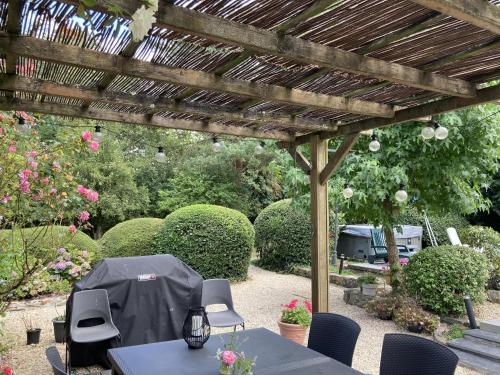 un patio avec une table et des chaises sous une pergola en bois dans l'établissement Chambres d'Hotes - La Marmoire, à Soudan