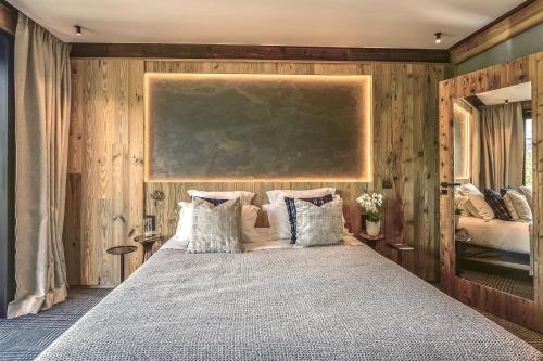 a bedroom with a large bed with wooden walls at Hôtel L'Arboisie in Megève