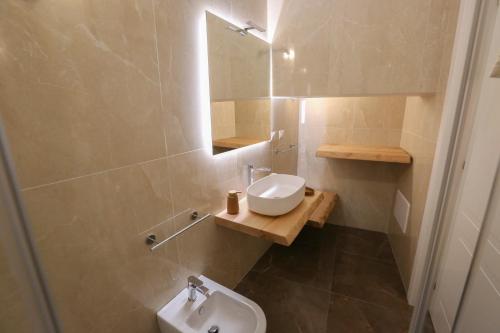 a bathroom with a sink and a toilet and a mirror at Le Due Dimore in Collepasso