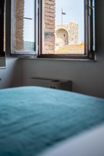 a bedroom with a bed and a window with a castle at Rooms and Wine al Castello in Monteriggioni