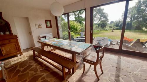 une salle à manger avec une table et des chaises et une grande fenêtre dans l'établissement La Villa d'Éole - Île aux moines, à l'Île-aux-Moines