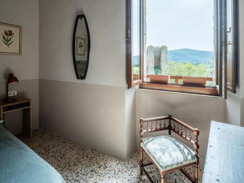a bedroom with a chair and a window at Rooms and Wine al Castello in Monteriggioni