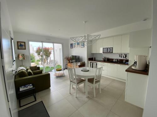 une cuisine et un salon avec une table et des chaises dans l'établissement Maison neuve zone coulée verte menant a l'océan, à Saint-Gilles-Croix-de-Vie