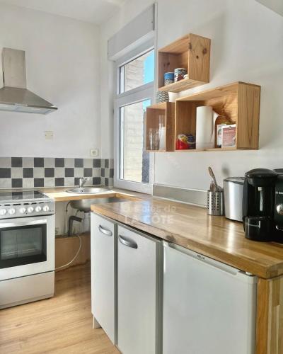 une cuisine avec des armoires blanches et un comptoir en bois dans l'établissement Appartement en hyper centre du Touquet, à Le Touquet-Paris-Plage