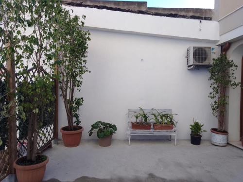 a patio with potted plants and a white bench at Civico 381 - private parking in Quartu SantʼElena