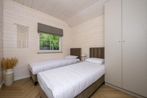two beds in a white room with a window at Boogie House domki nad morzem in Jarosławiec
