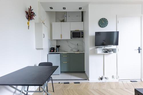 Il comprend une cuisine avec des placards blancs, une table et une télévision. dans l'établissement Romantic 3 Stars - Studio suite by Canal Saint-Martin, à Paris
