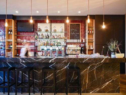 a bar in a restaurant with a person walking behind it at C-Hotels Westwing - ex Mercure in Roeselare