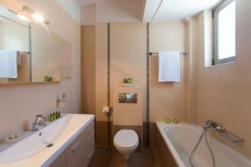 a bathroom with a tub and a toilet and a sink at Marigo Villa in Salvia Villas in Skouloúfia