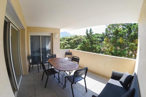 un balcon avec une table et des chaises et une grande fenêtre dans l'établissement Elisa T3 bord de mer cosy et confortable, à Calvi