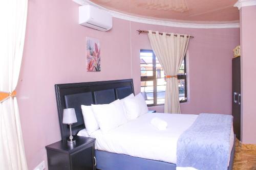 a bedroom with a white bed and a window at Masiyabundu Guest House in Gaborone