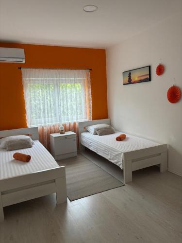 two beds in a room with an orange wall at Villa Vita in Mostar