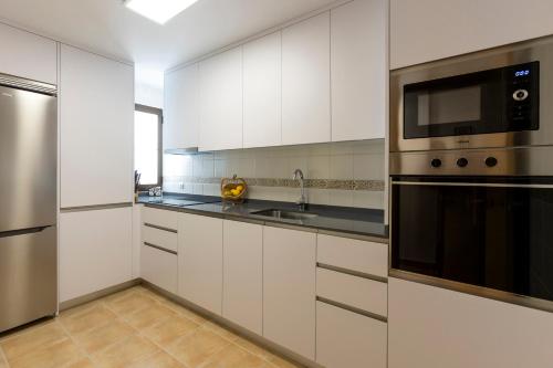 a kitchen with white cabinets and stainless steel appliances at Todimer Mediterranean Relax in Ítrabo