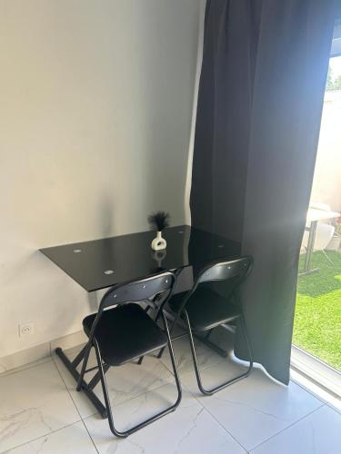 a black desk with two chairs next to a window at Studio en bas de villa in Arles