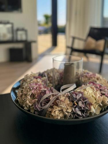 a bowl of flowers on a table with a glass at Renovated Holiday Home With Sea View In Skåstrup in Bogense