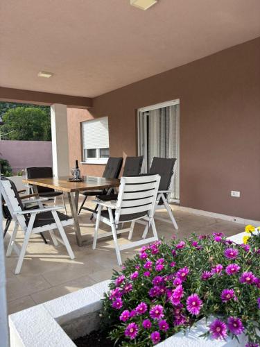 a patio with a table and chairs and purple flowers at Villa Vita in Mostar
