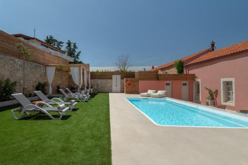 a backyard with a swimming pool and lawnitures at Arhontiko Arhanes Suites in Archanes