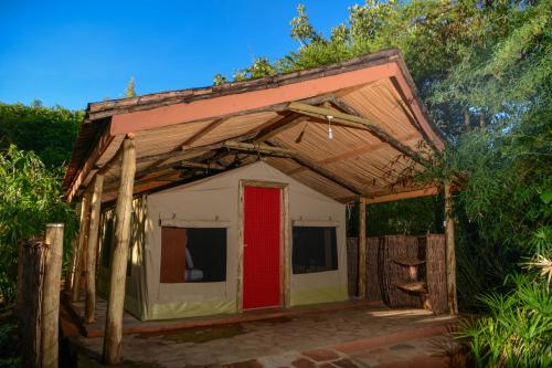 a small house with a red door in the middle at Oldarpoi Wageni Camps in Keekorok