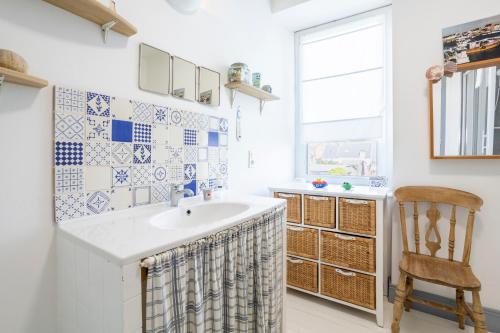 a bathroom with a sink and a chair at Plage 300m Bleu Salé 4 Ch in Le Guilvinec