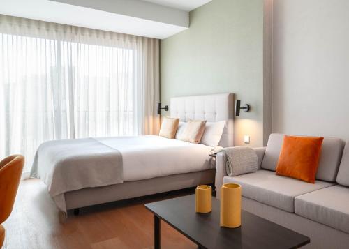 a bedroom with a large bed and a couch at Limehome Lisbon Saldanha in Lisbon