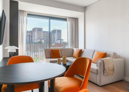 a living room with a couch and a table and chairs at Limehome Lisbon Saldanha in Lisbon