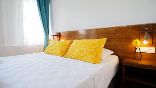 a bedroom with a bed with yellow pillows and a wooden headboard at Limonata Bozcaada ex Vina Garden in Bozcaada