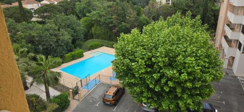 une vue aérienne d'une piscine dans un parking avec un arbre dans l'établissement LE BELLEVUE - APPARTEMENT - FREJUS -T2-Piscine, à Fréjus