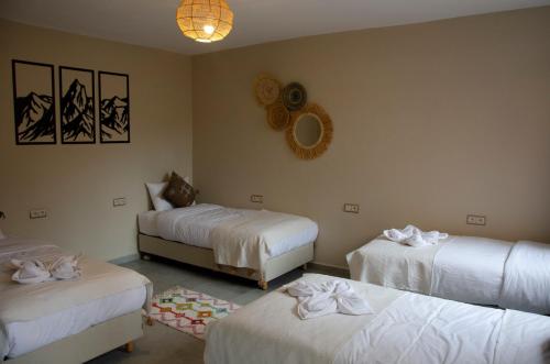 a room with three beds with white sheets at harmony surf lodge in Taghazout
