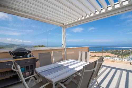 a table and chairs on a balcony with a view of the ocean at Sublime Appart Neuf in Albitreccia