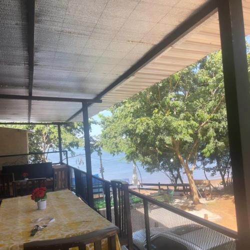 Un balcón con mesa y vista a la playa. en CABAÑA ROHAYHU- Frente al rio Paraná -Coratei-Ayolas Misiones-Paraguay, en Ayolas