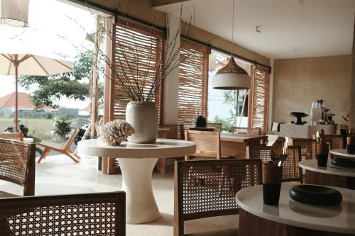 a dining room with tables and chairs and windows at The Iggy Hotel Seseh Studio 4 in Cemagi